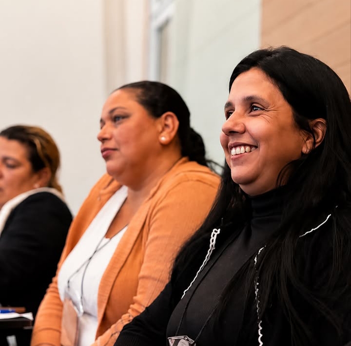 Mulheres sorrindo durante a palestra do evento